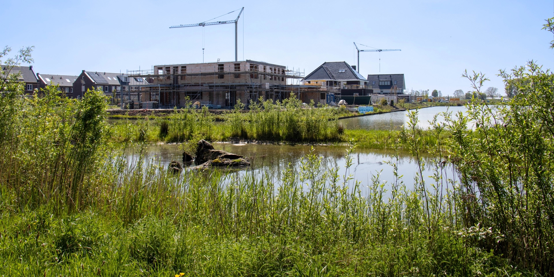 Groene omgeving met water en aanbouw woningen