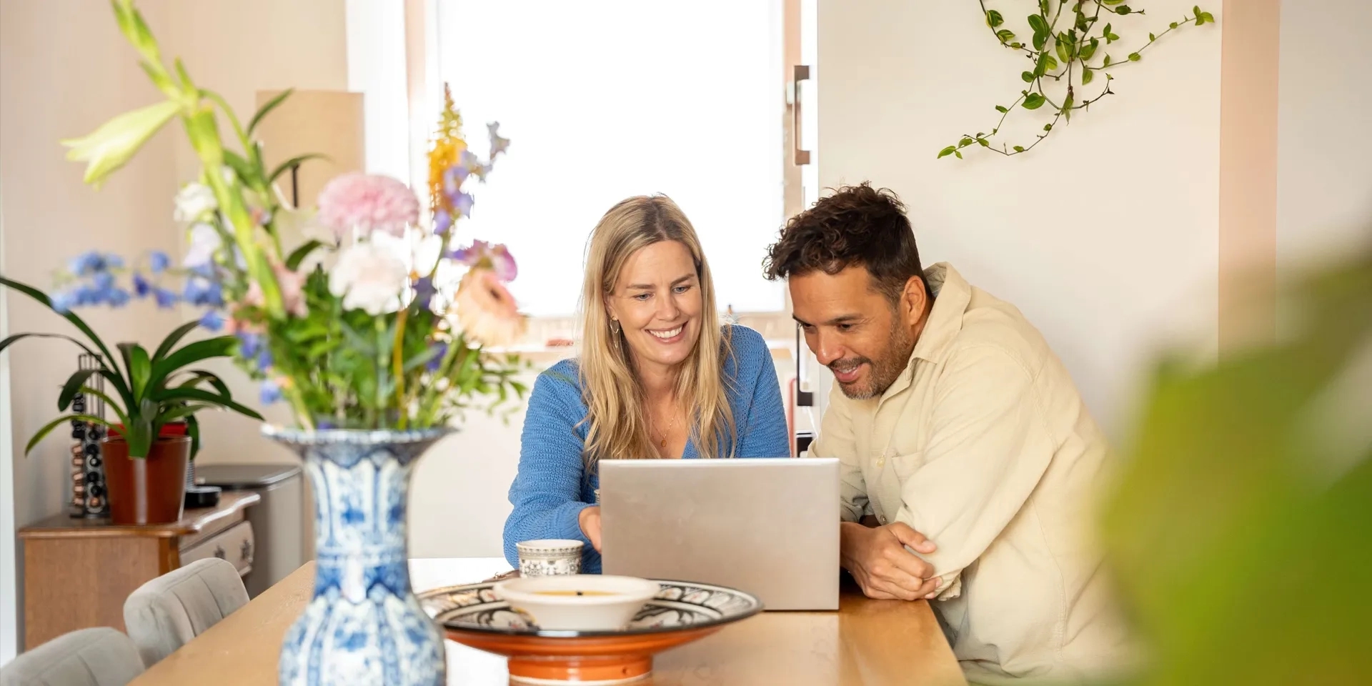 Vrouw en man zitten aan tafel met laptop