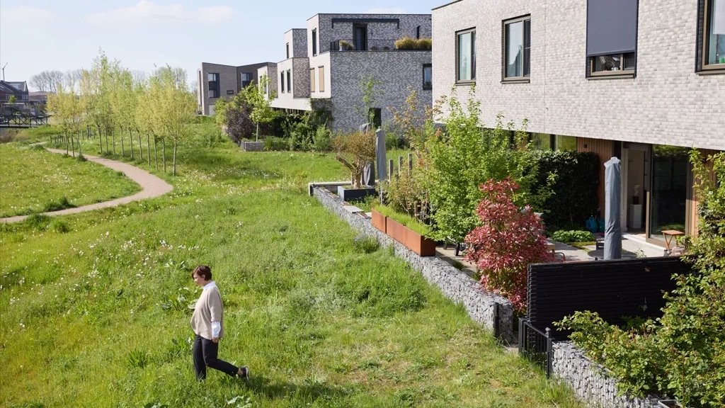 Vrouw loopt in grasveld voor een aantal rijwoningen