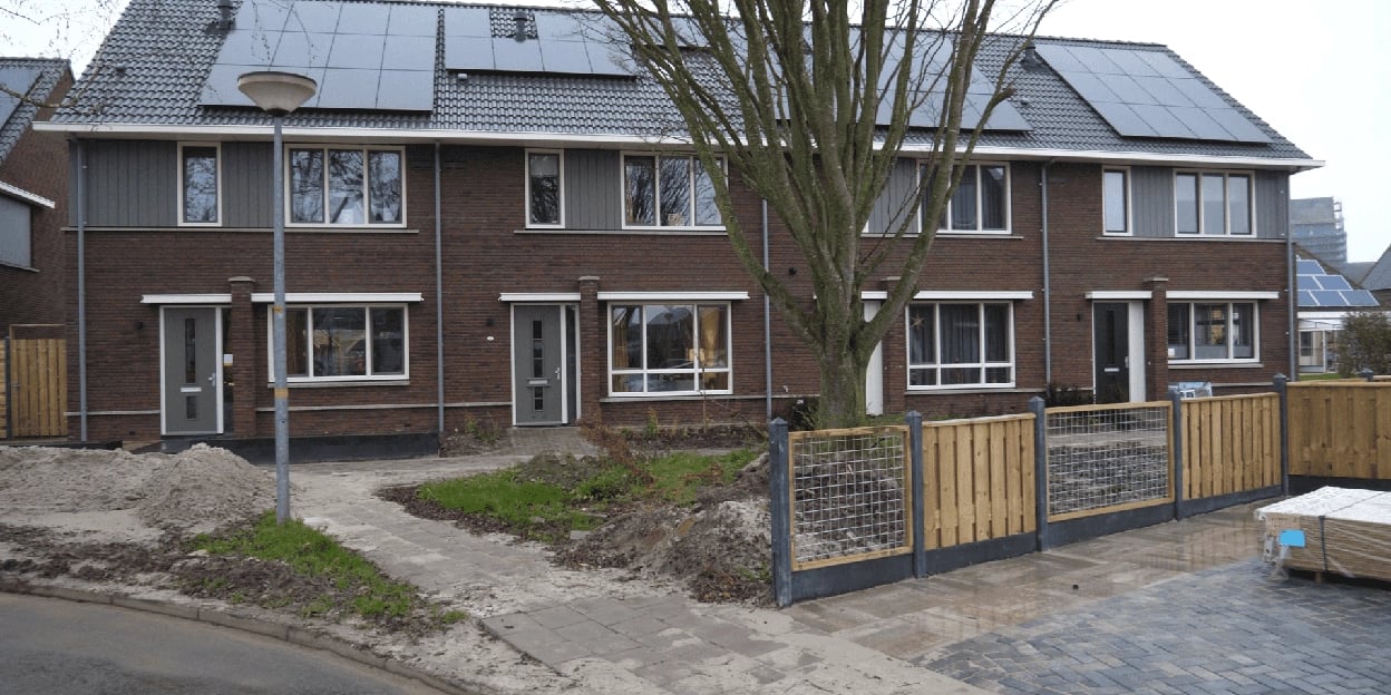 Vooraanzicht van de rijwoningen met een boom