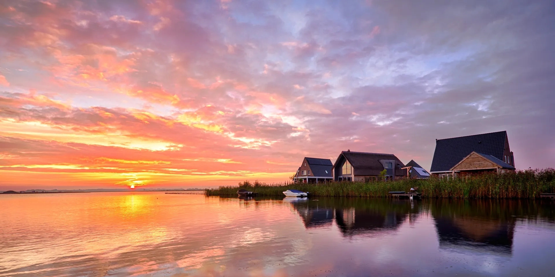 Zonsondergang aan het water met vrijstaande woningen
