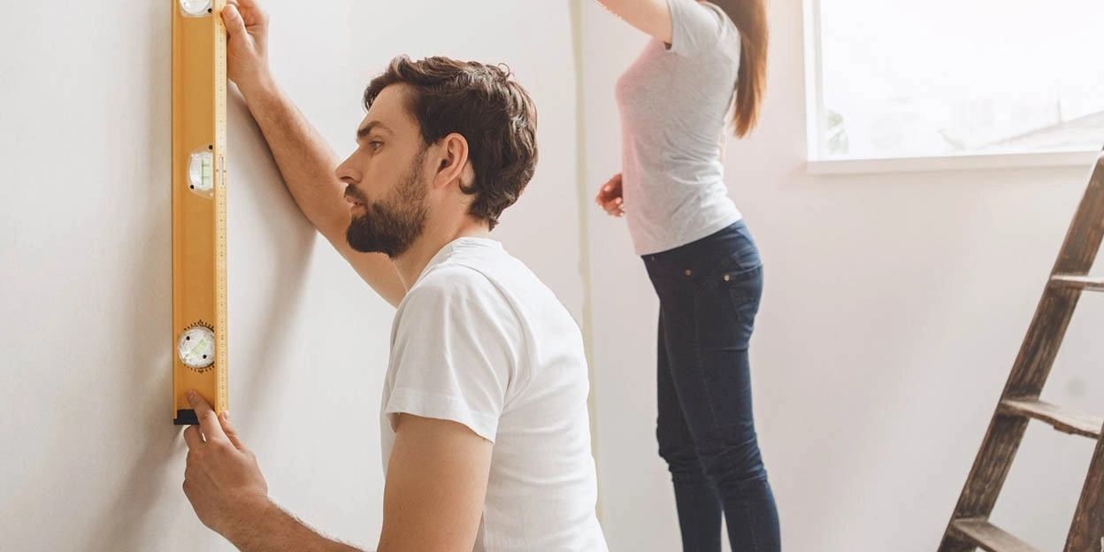 Man en vrouw brengen het behang aan in hun nieuwbouwwoning