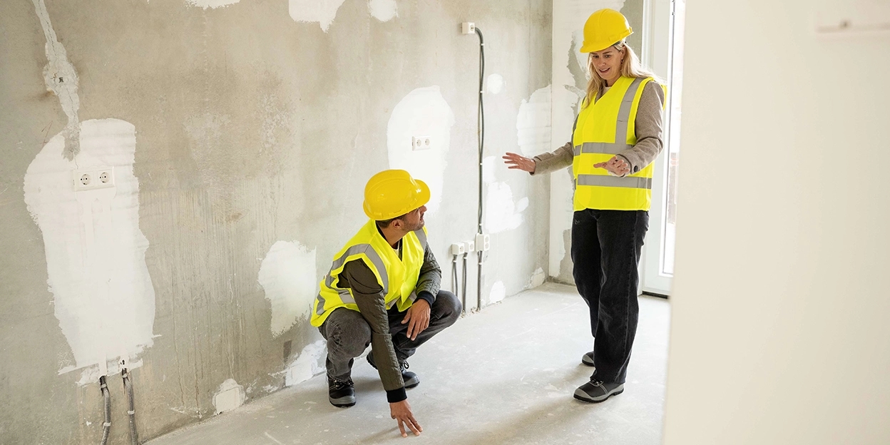 Man en vrouw bekijken de vloer van hun nieuwbouwwoning