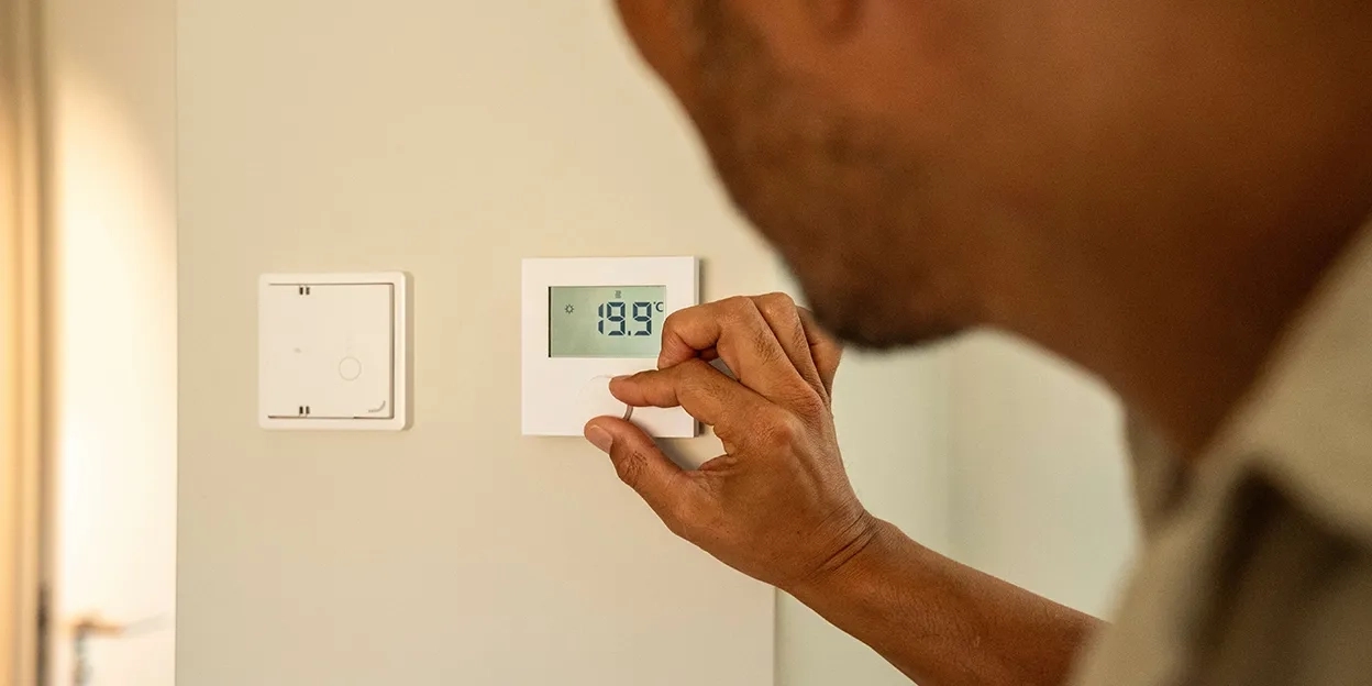 Man zet de thermostaat in zijn woonkamer lager