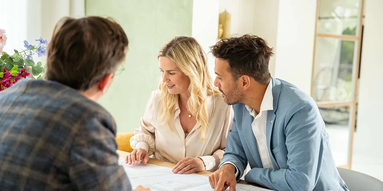 Man en vrouw bekijken de plattegronden van hun nieuwbouwwoning