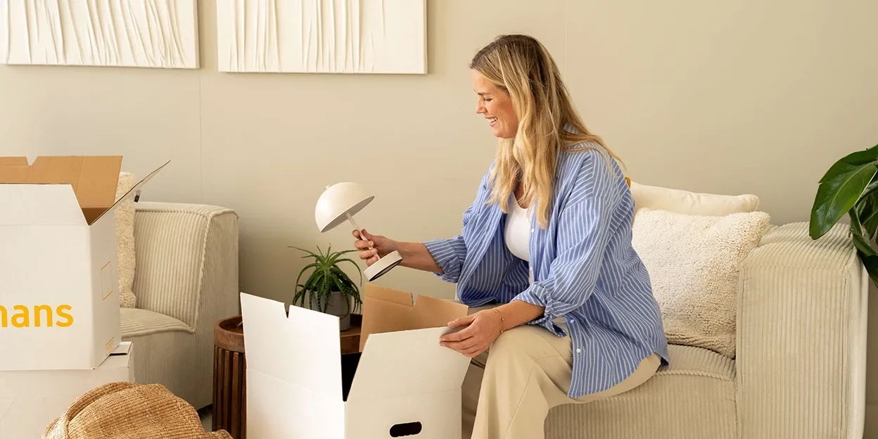 Vrouw pakt een lamp uit een van haar verhuisdozen