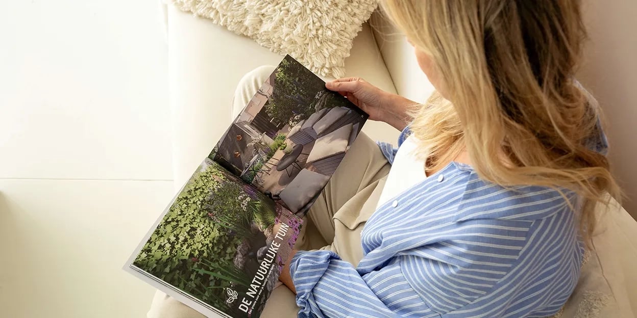 Vrouw leest op de bank de brochure over duurzame tuinen