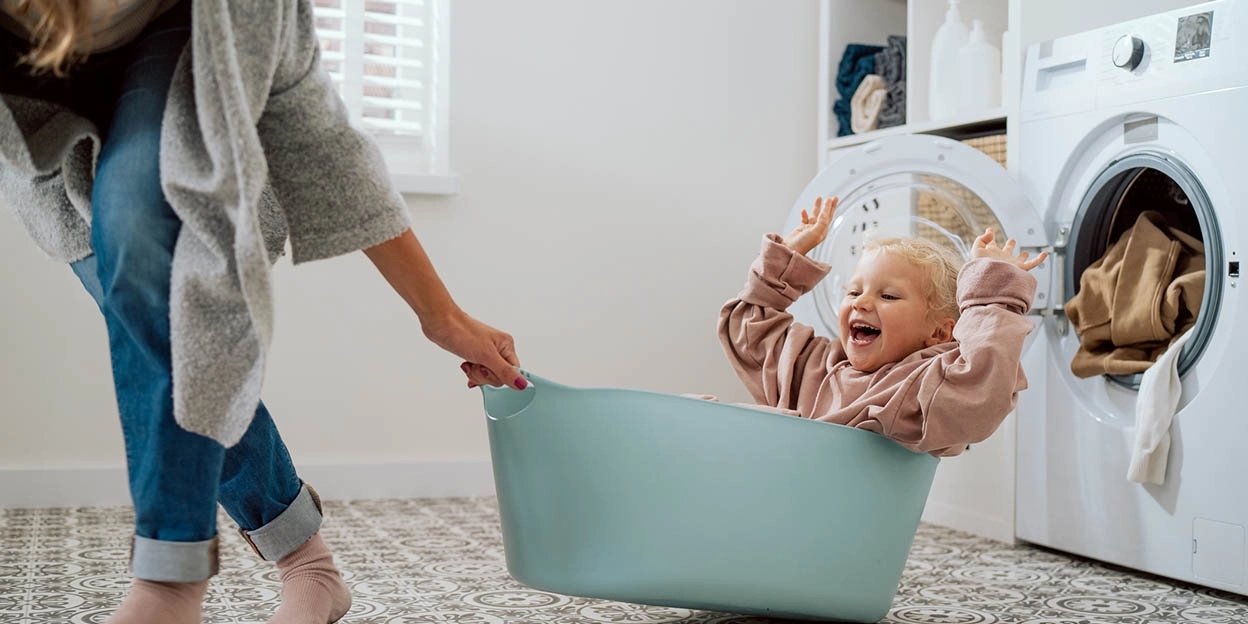 Moeder speelt met enthousiast kind in de wasmand
