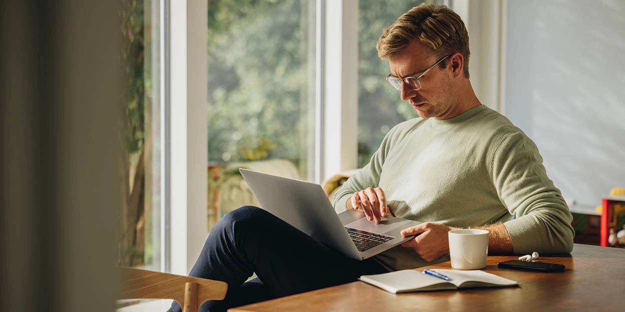 Man zit met zijn laptop aan de eettafel