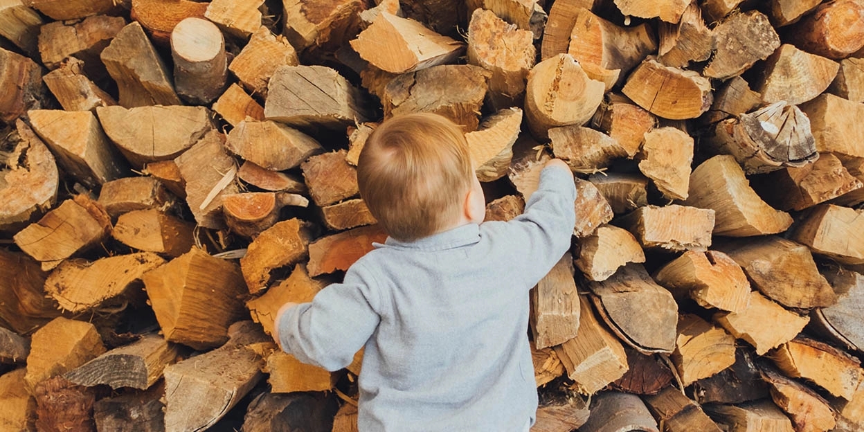 Jonge peuter pakt opgestapelde houtblokken vast